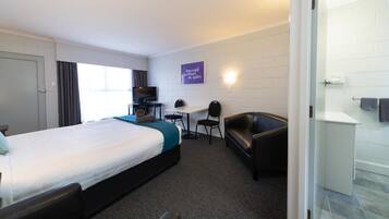 Una habitación de hotel con cama, escritorio, silla, sofá y televisor.
