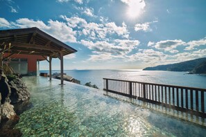 A clear view of a coastal infinity pool with a wooden deck and a metal railing, overlooking the sea. - Akazawa Onsen Hotel (Ito)