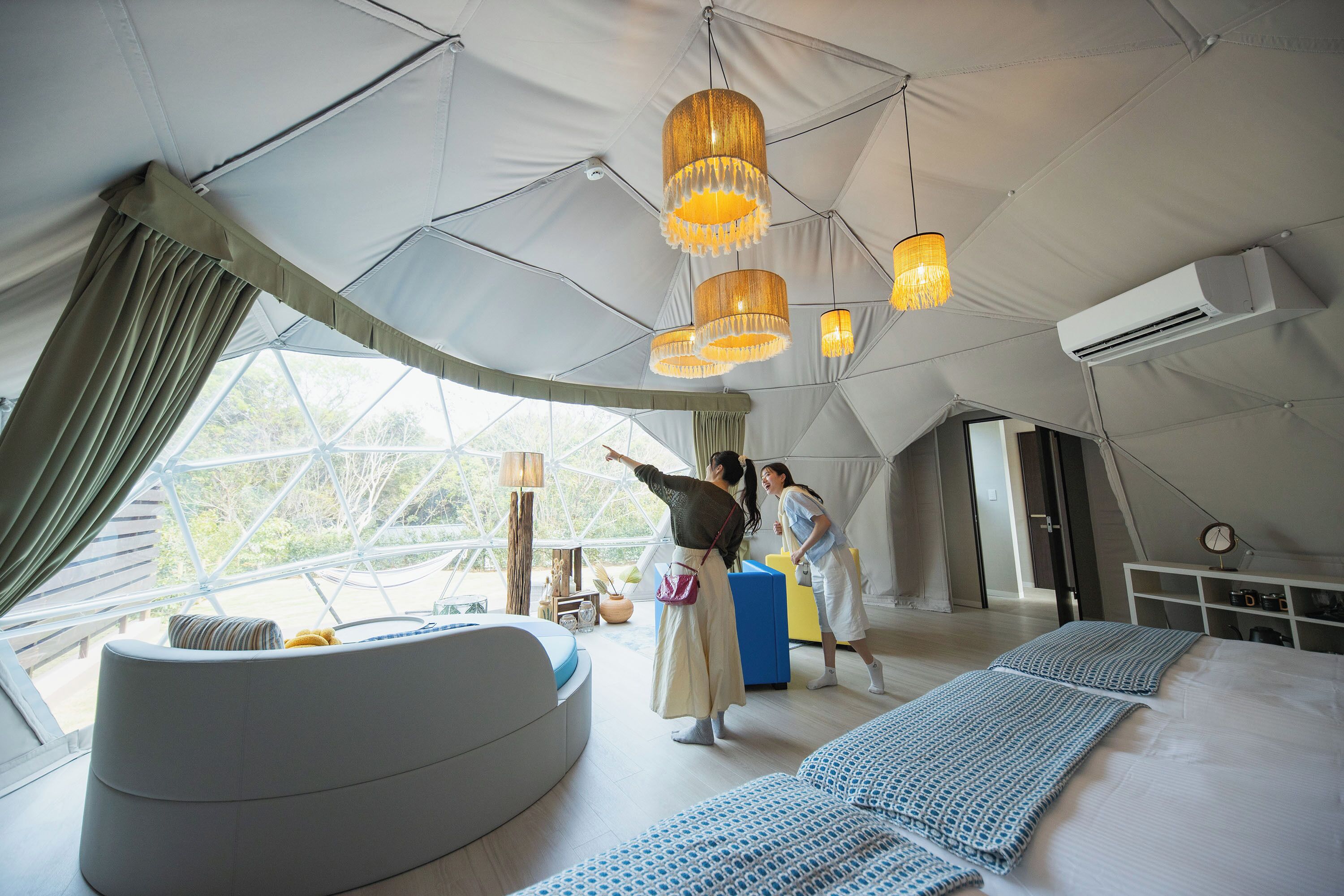 A tented accommodation with a bed, a seating area, and a view of the outdoors.