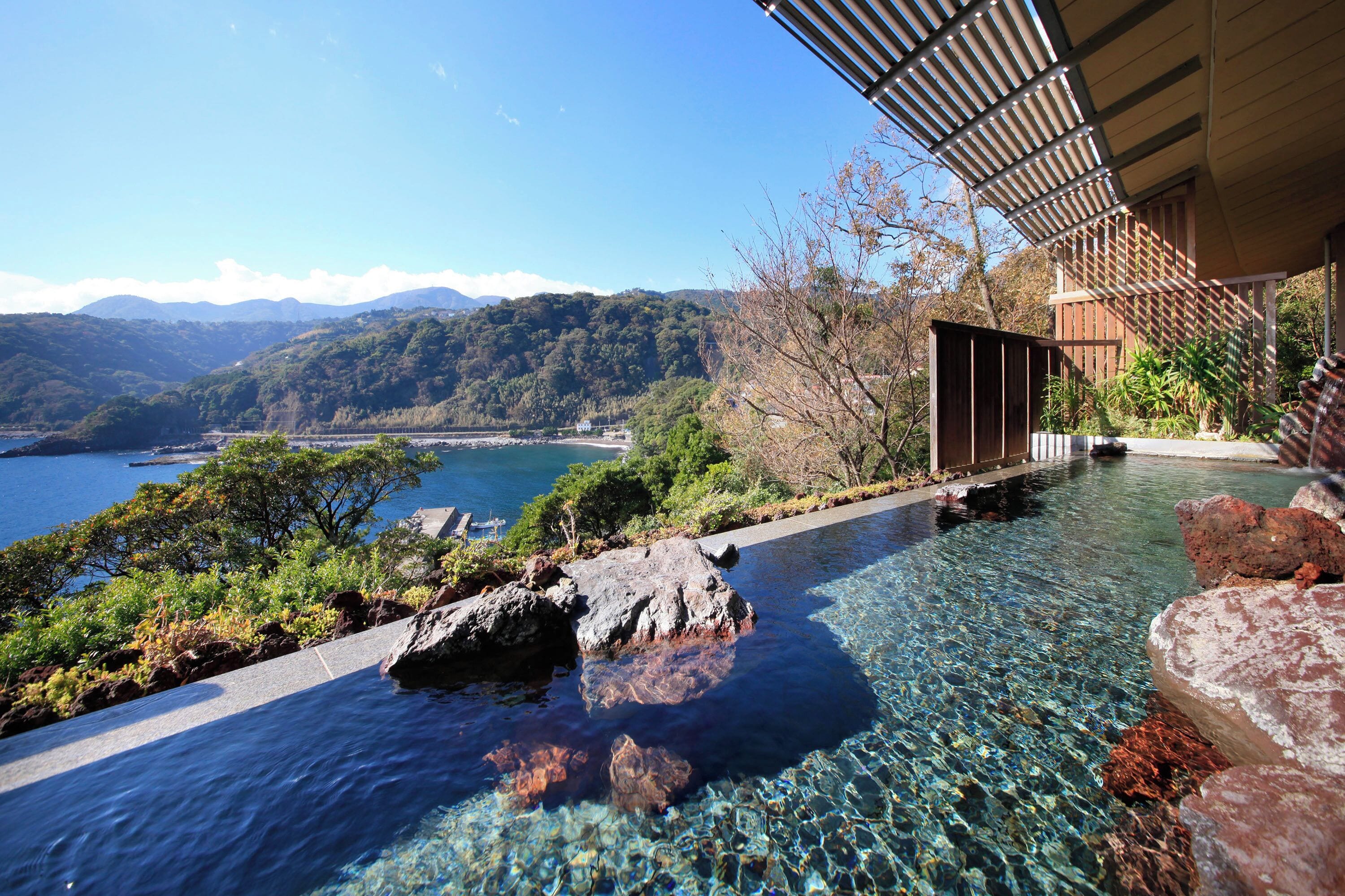 A clear pool with a view of mountains and a body of water.