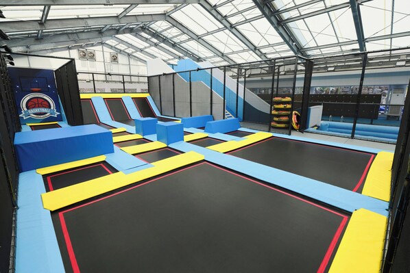 Un parque de trampolines cubierto con múltiples trampolines y obstáculos acolchados.