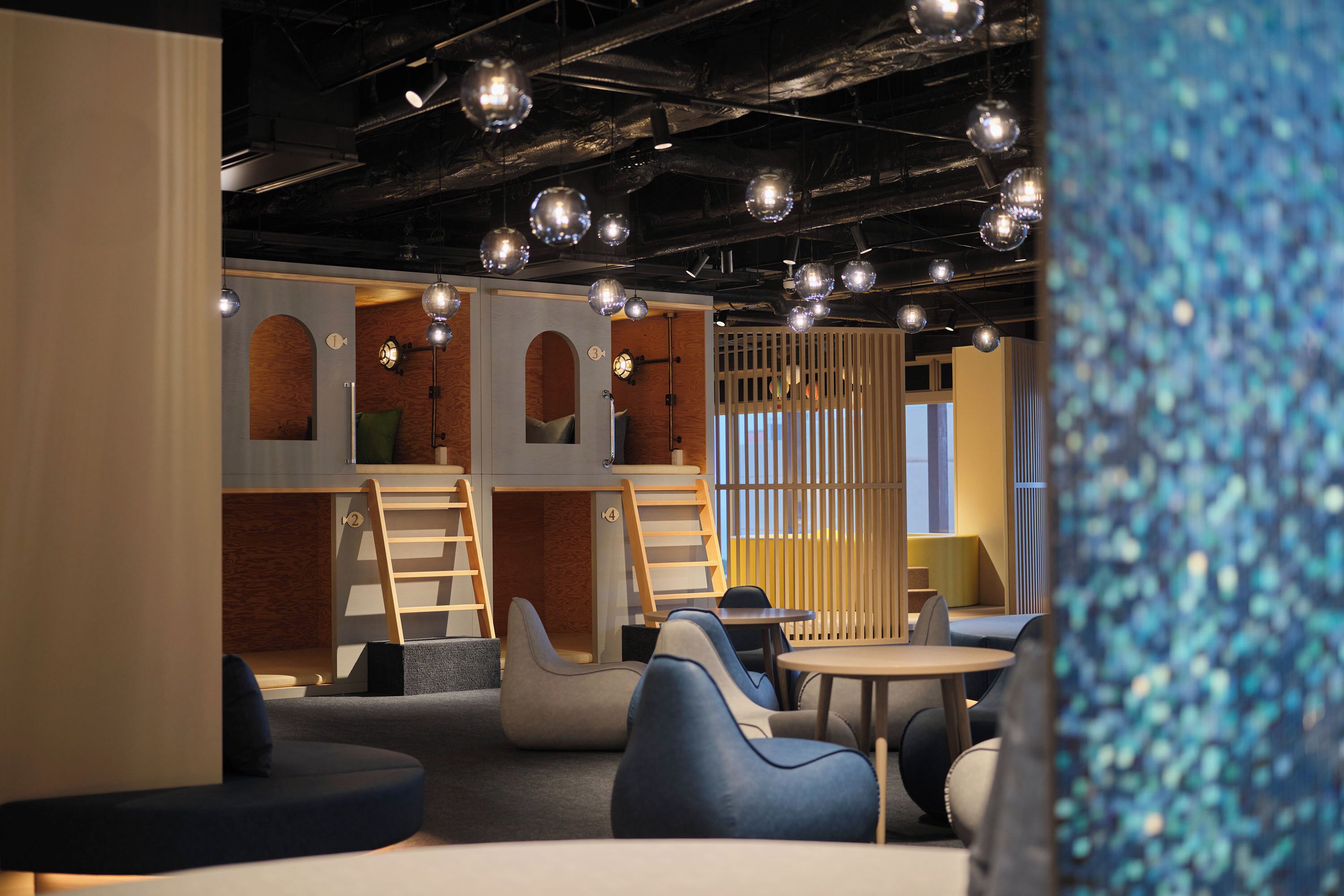 A modern interior with seating areas, a staircase, and hanging spherical lights.