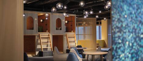 A modern interior with seating areas, a staircase, and hanging spherical lights.