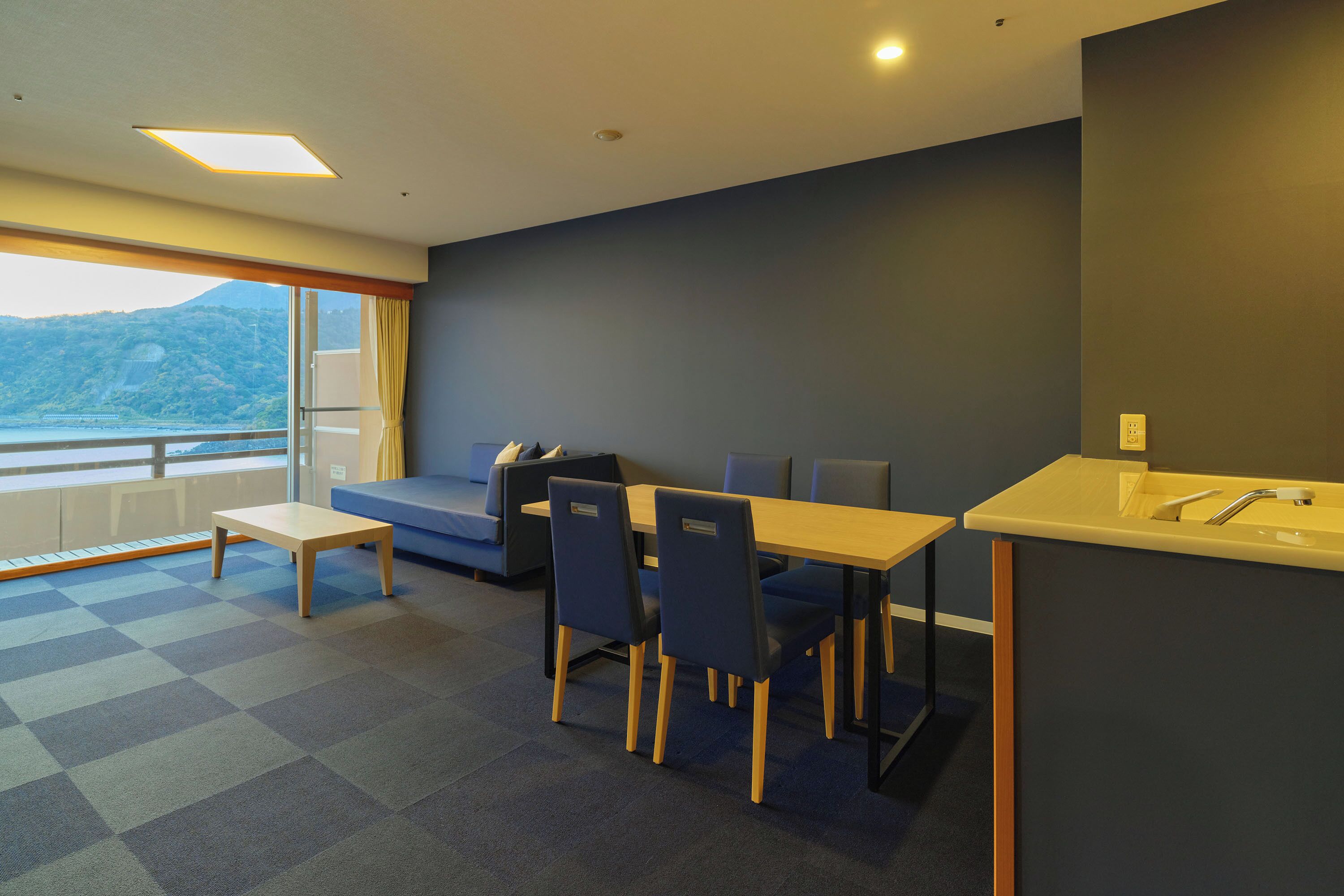 Una habitación de hotel moderna con comedor, sofá y vistas al exterior.