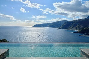 Vista despejada de una piscina con un paisaje montañoso y el mar al fondo.