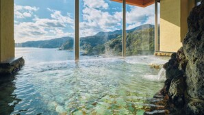 A hot spring with clear water, a view of mountains, and a large window.