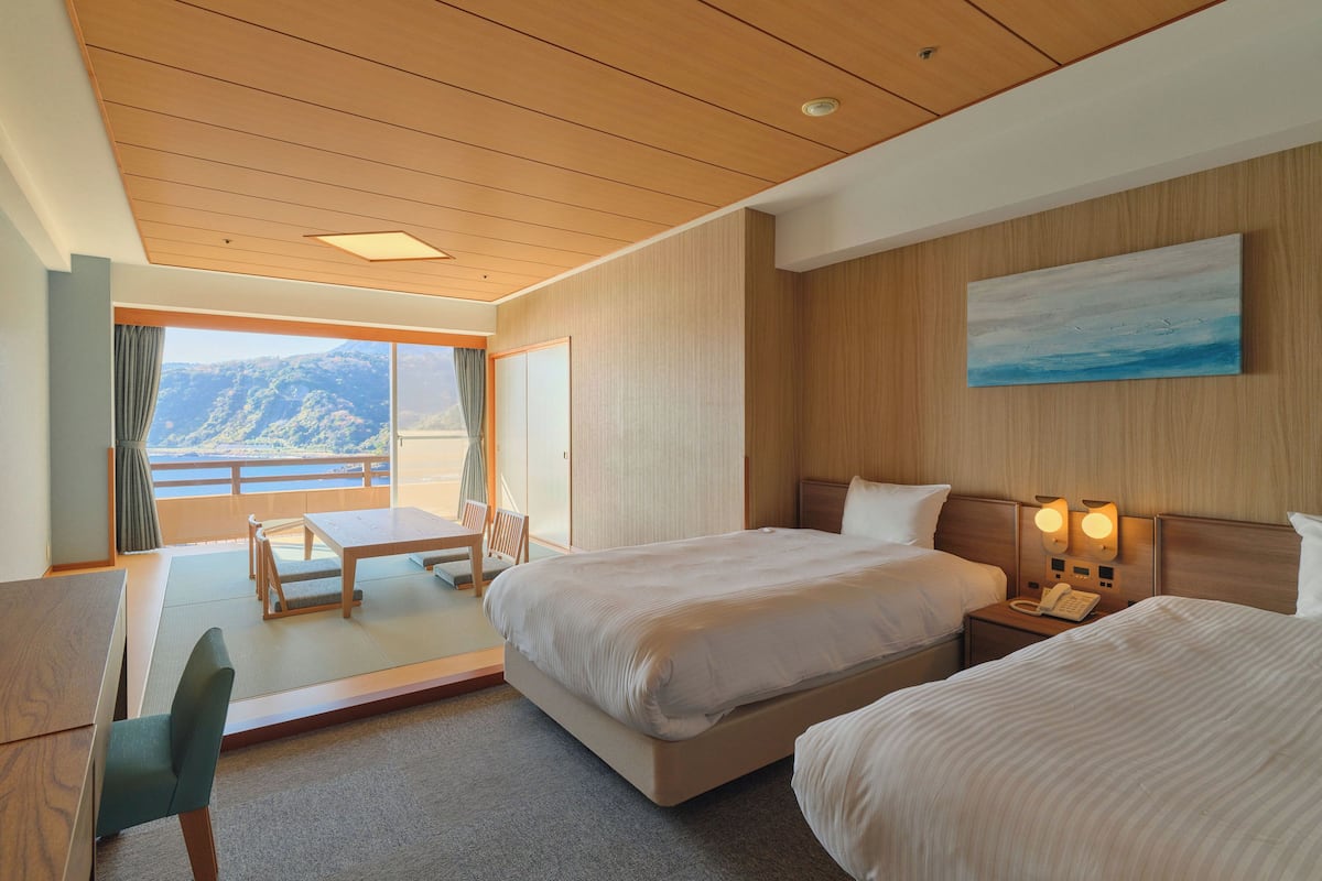 A hotel room with a bed, bedside table, and a painting on the wall.