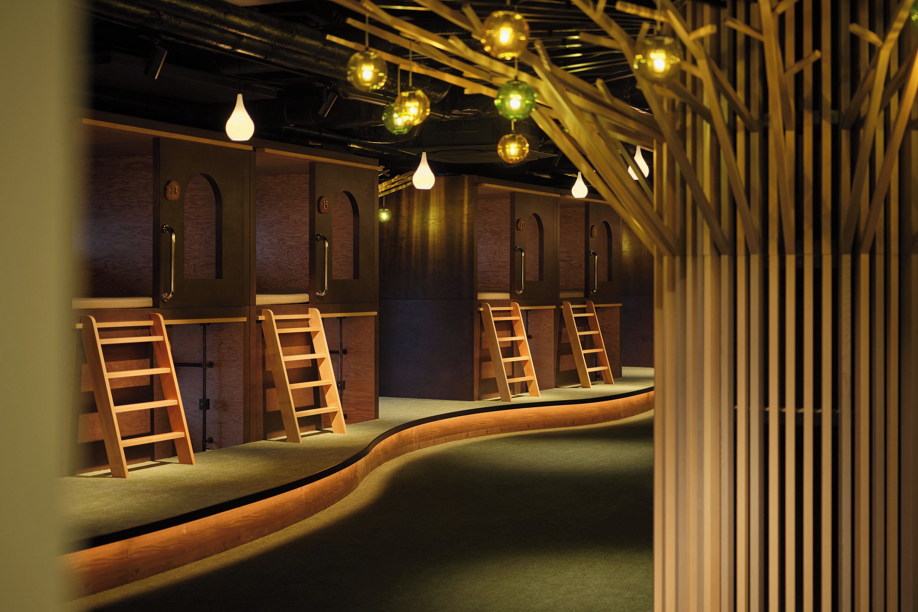 A room with bunk beds, wooden ladders, and hanging spherical lights.