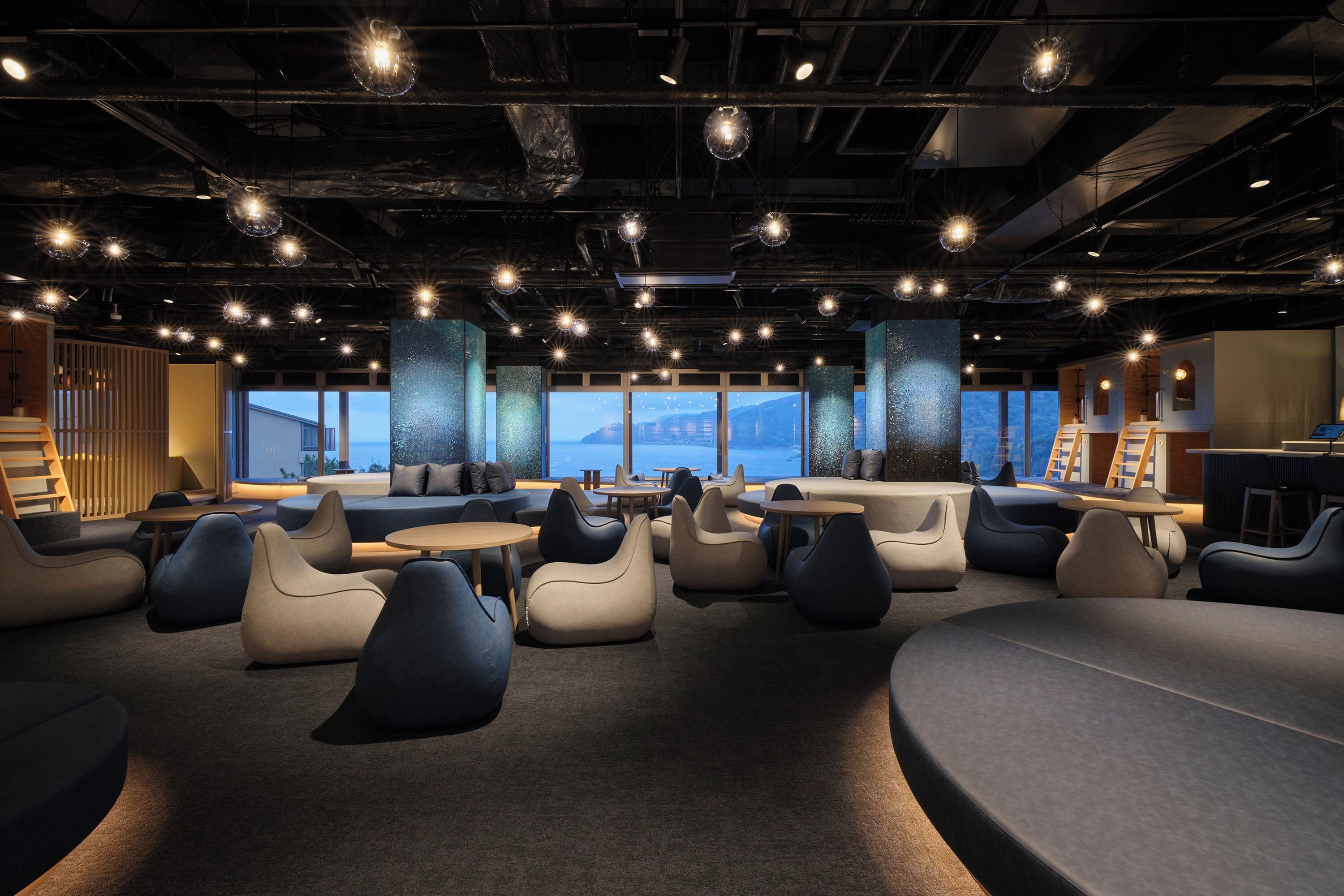 A modern lounge area with seating, tables, and a view of the mountains.