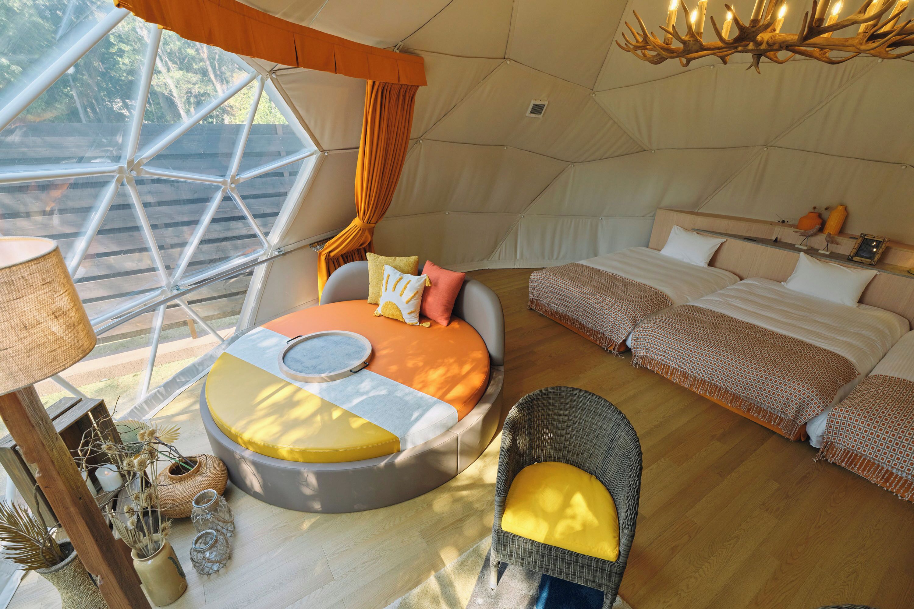 Una tienda espaciosa con una cama grande, un rincón de estar circular y una mesa de comedor.