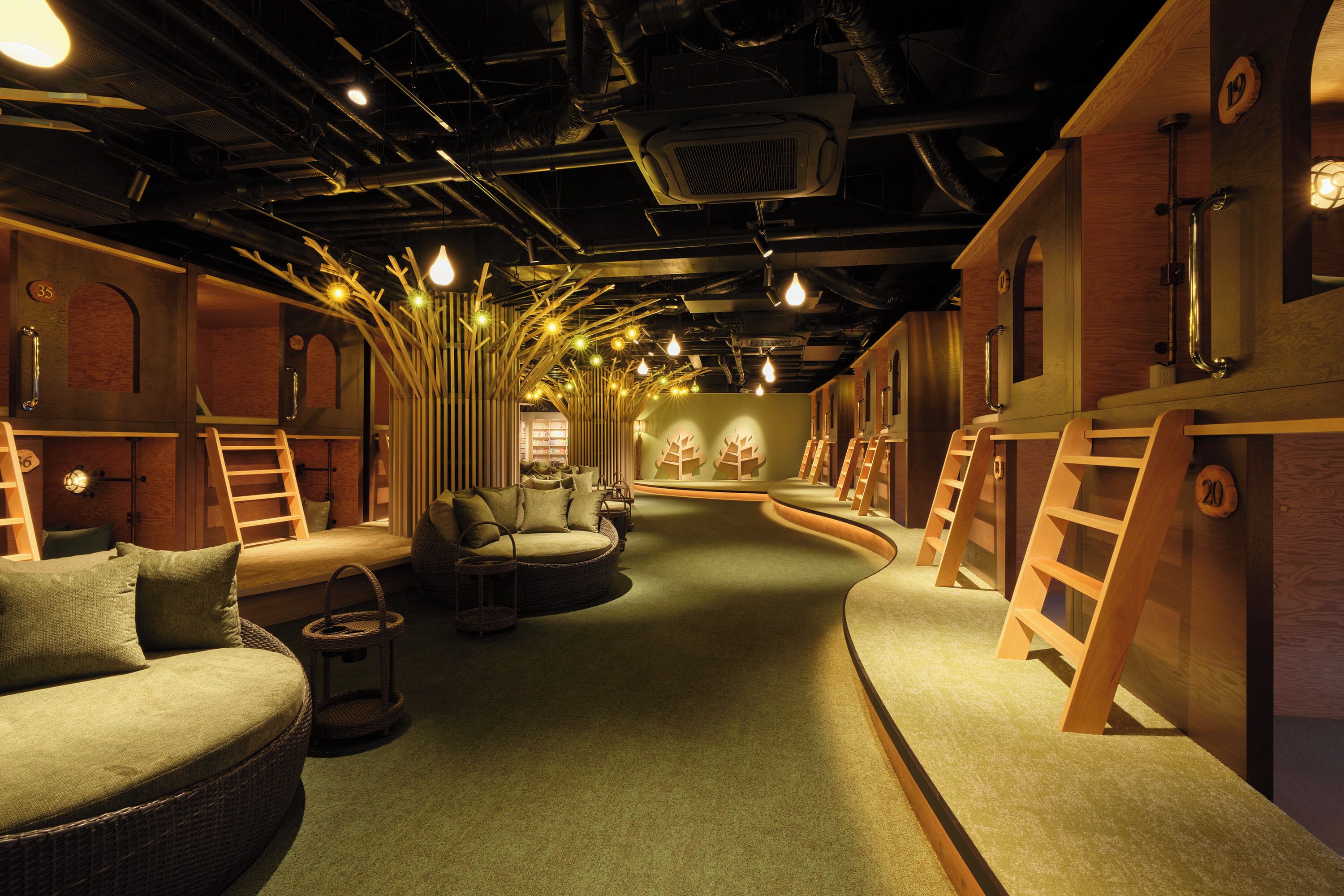 A room with a curved layout, wooden ladders, a wicker sofa, and a small table.
