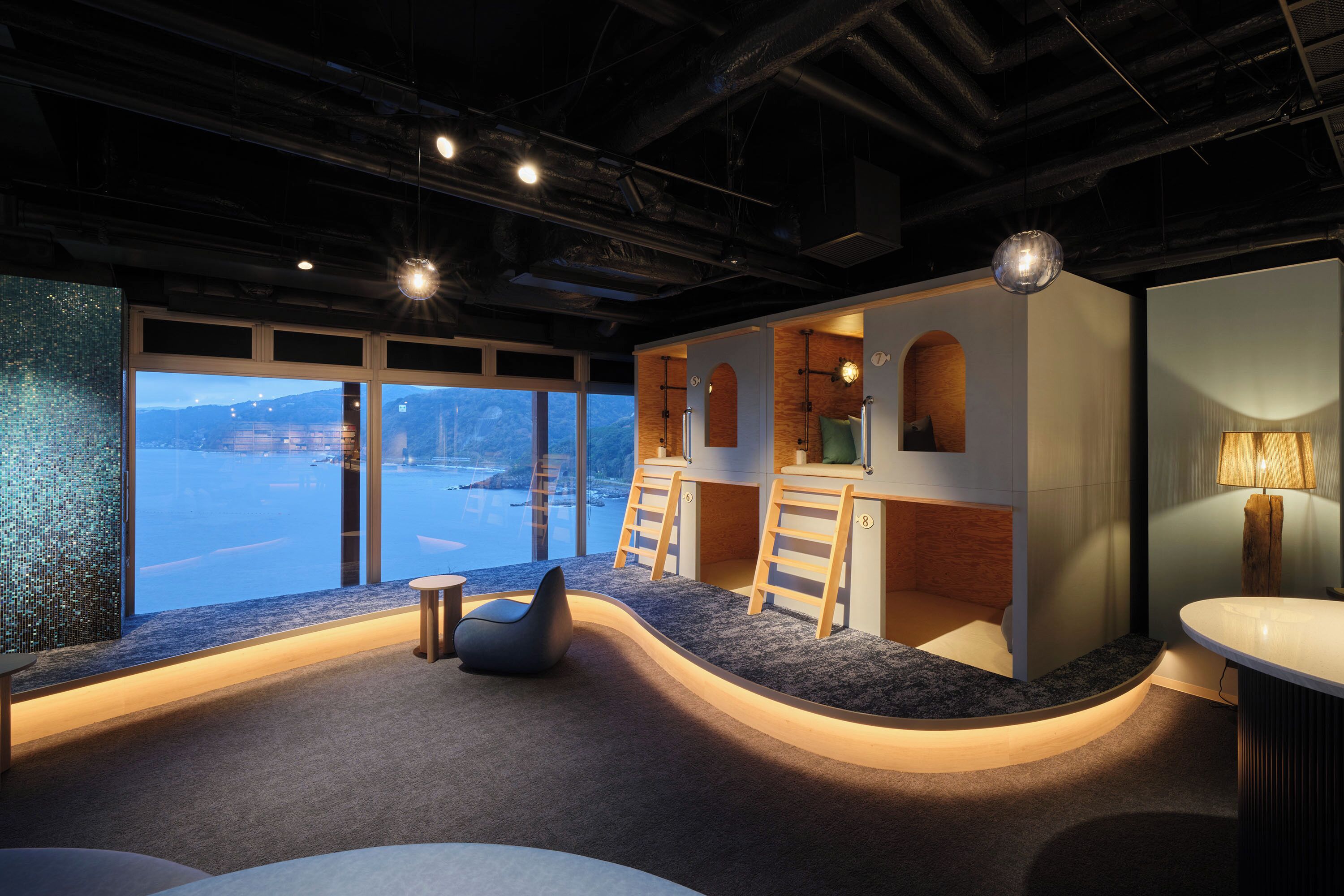 Een modern interieur met een gebogen zithoek, uitzicht op het water en een kitchenette.
