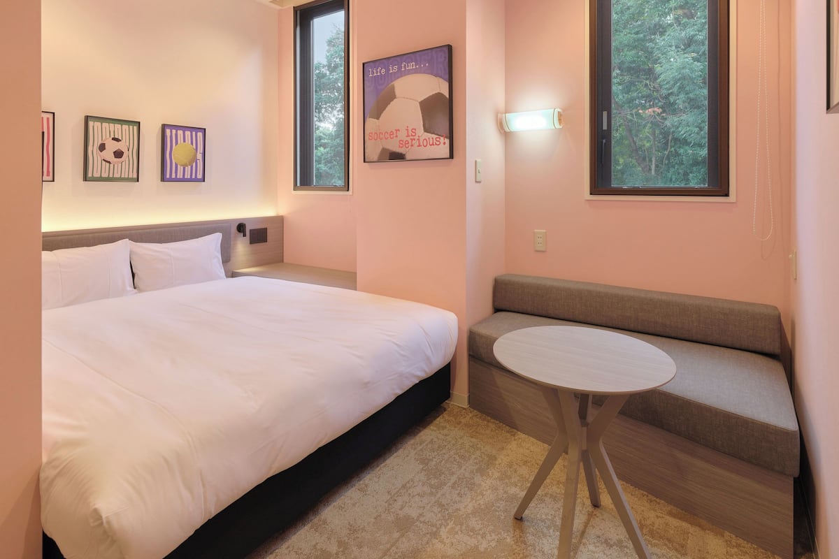 A bedroom with a bed, a sofa, a small table, and a wall with framed pictures.