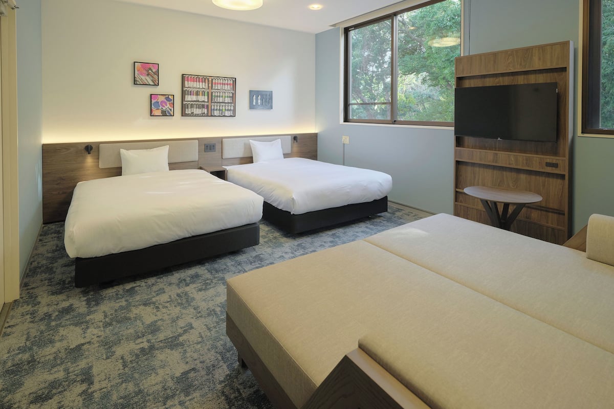 A hotel room with two beds, a TV, and artwork on the wall.