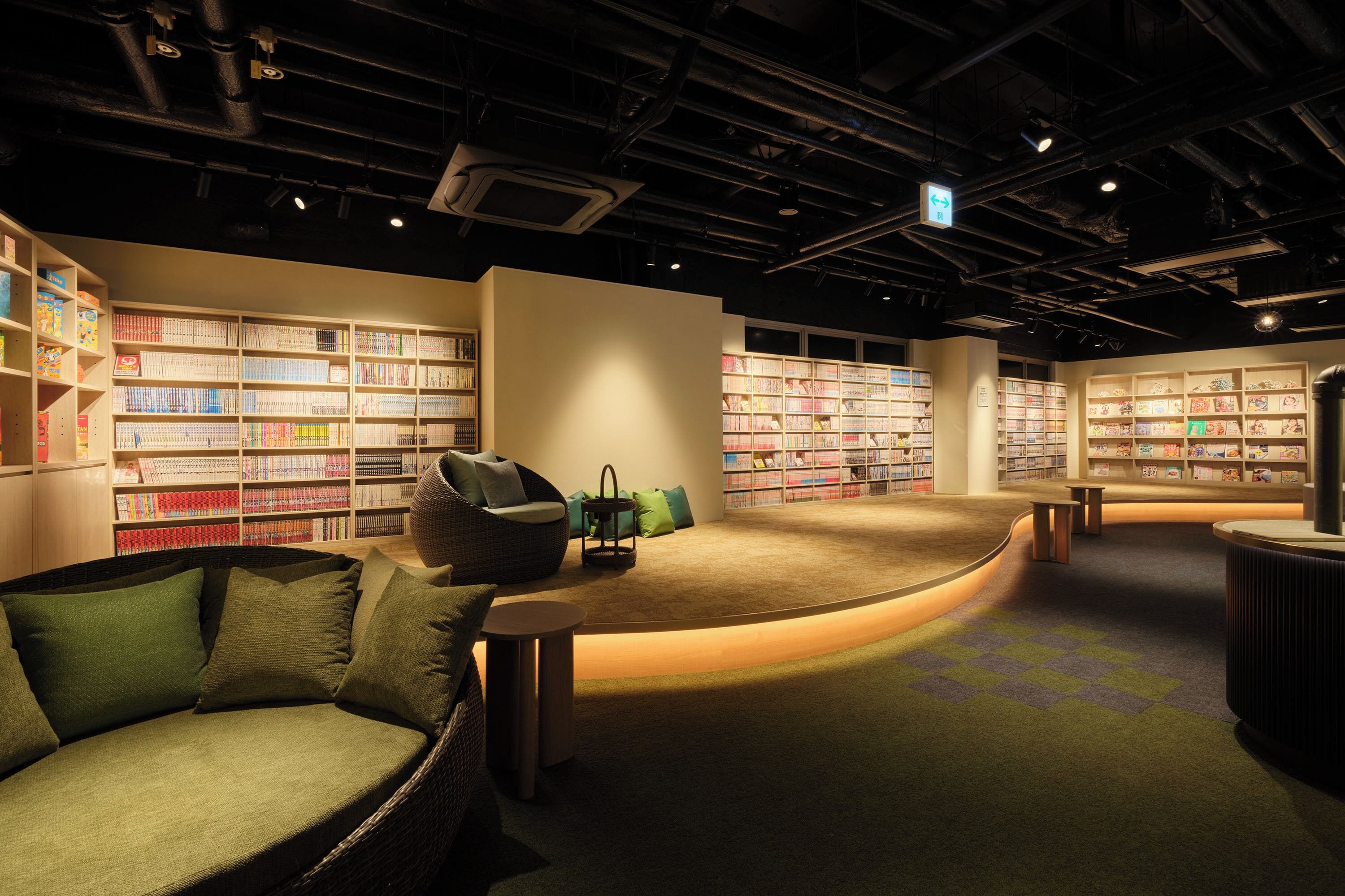 A library interior with bookshelves, seating areas, and a curved reading space.