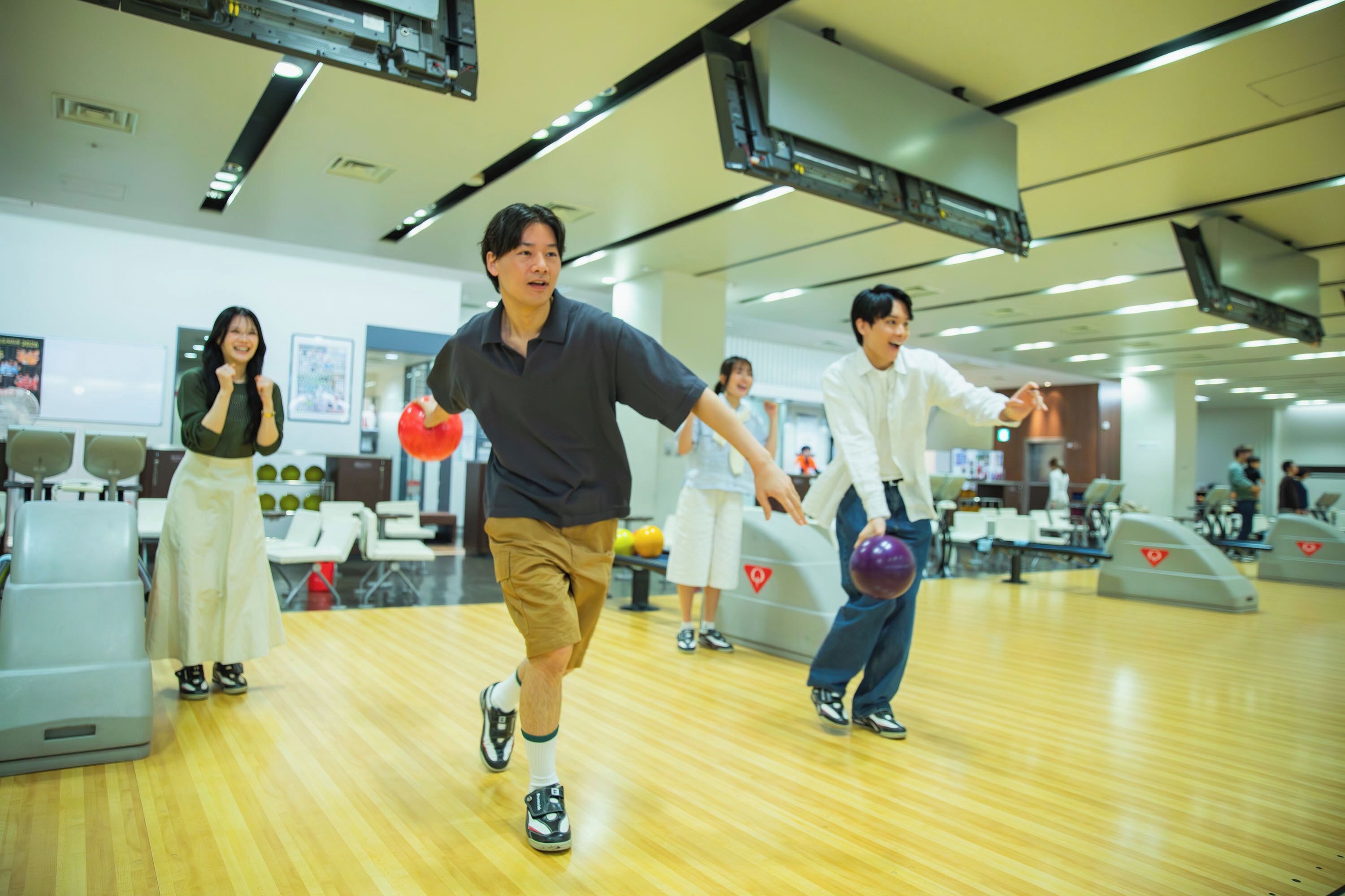 A bowling alley with lanes, bowling balls, and players.