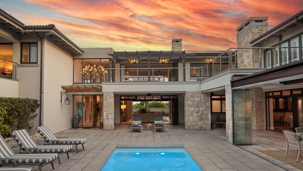 A modern house with a swimming pool, outdoor seating, and a balcony.