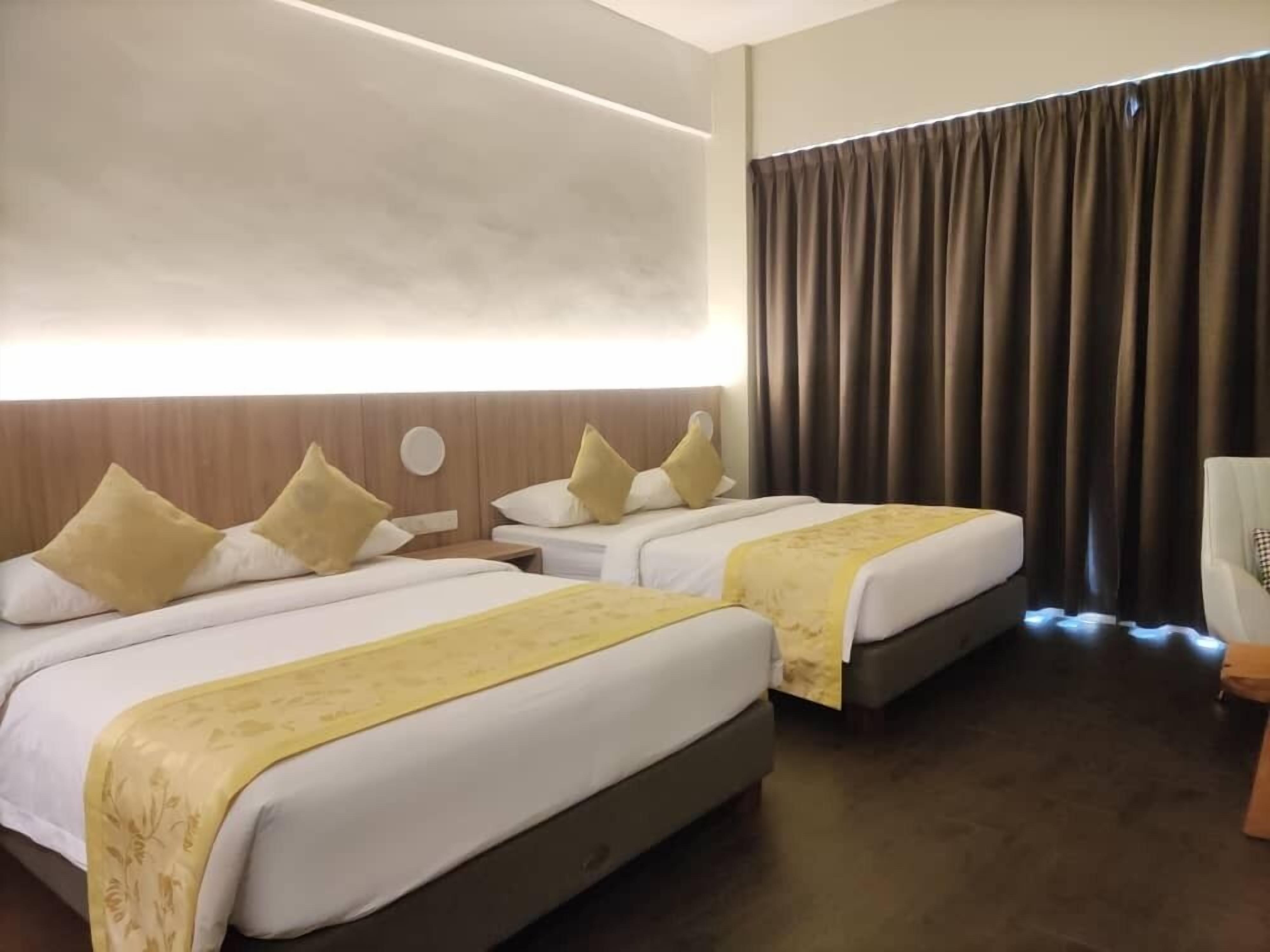 A hotel room with two beds, a large window with curtains, a wooden headboard, and a chair.