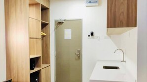 A compact kitchen with wooden cabinetry, a sink, and a door leading to another room. - Big Tree Hotel  (Temerloh)