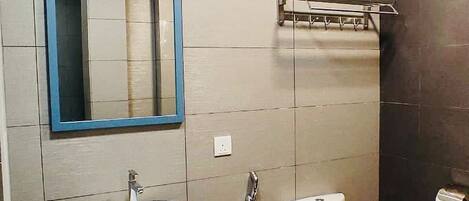 Un baño con lavamanos, espejo, inodoro y toallero.