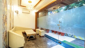 A modern interior with a curved sofa, a small table, and potted plants. - Treebo Lotus Blue (Bhopal)