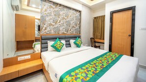 A modern hotel room with a large bed, a wardrobe, a vanity with a mirror, and a decorative wall. - Treebo Lotus Blue (Bhopal)