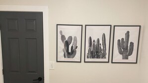 Una stanza con una porta scura, una panca e tre quadri raffiguranti cactus.