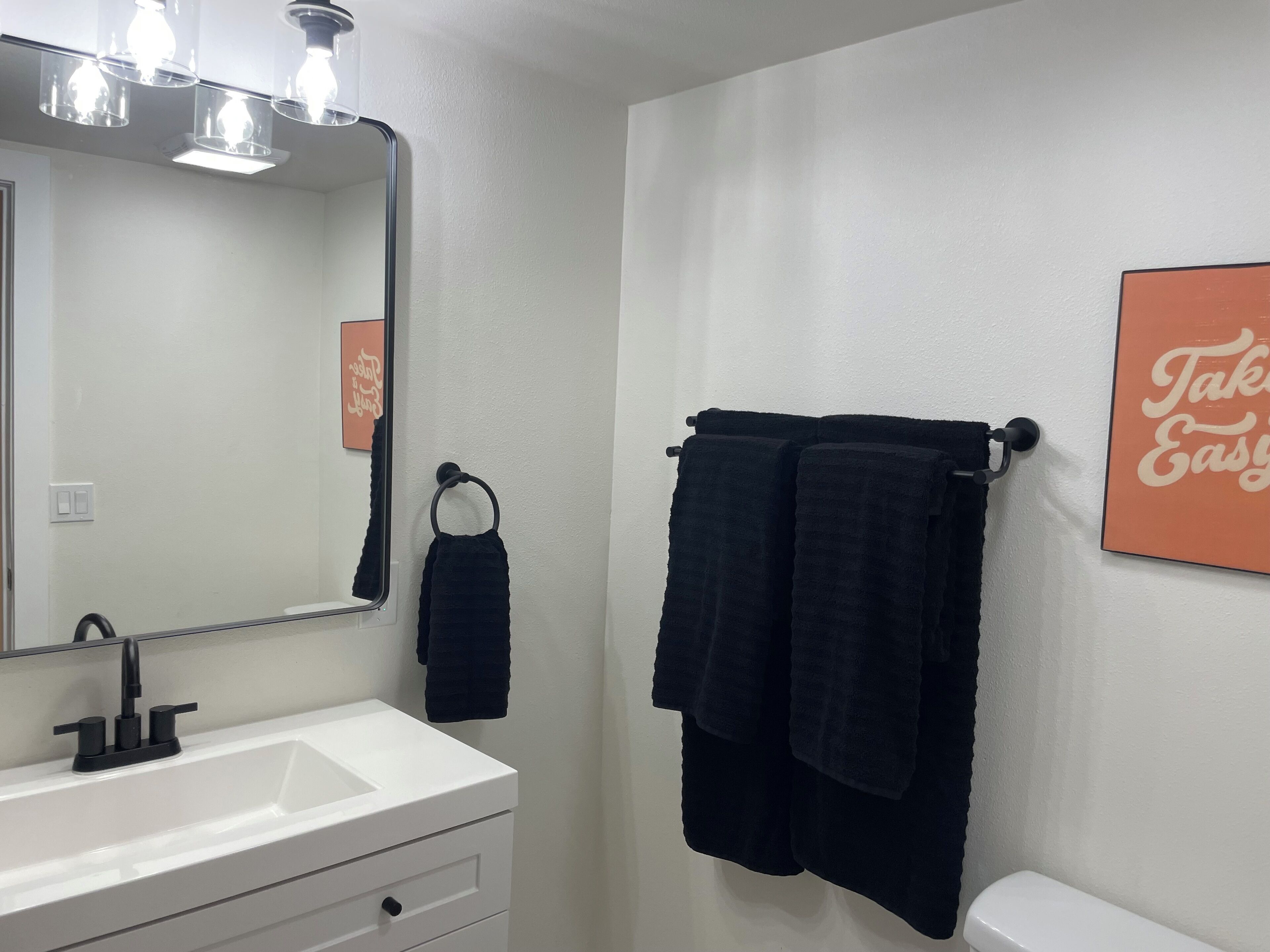 A bathroom with a white sink, black towel, and a mirror.
