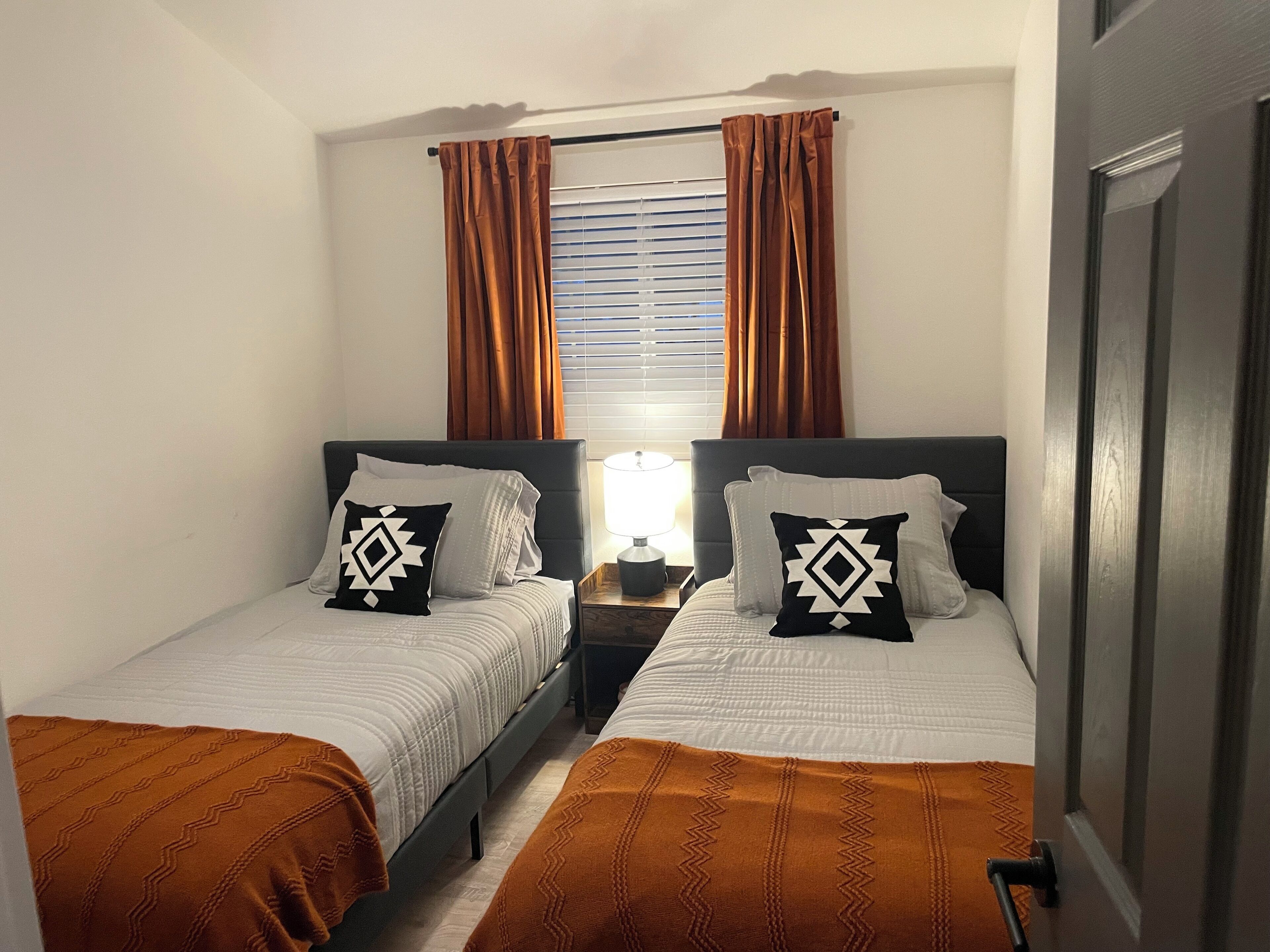 Habitación doble con dos camas, cada una con una almohada y una mesita de noche.