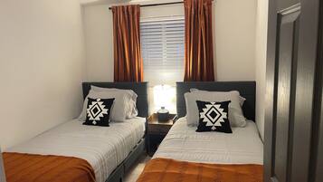 Habitación doble con dos camas, cada una con una almohada y una mesita de noche.