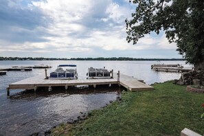 A dock with two boats, a grassy area, and a lake with a cloudy sky.