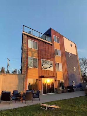 A modern multi-story building with a flat roof, large windows, and a visible balcony.