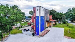 Ein modernes, mehrgeschossiges Gebäude mit flachem Dach und einer Fassade in Rot, Blau und Grau.