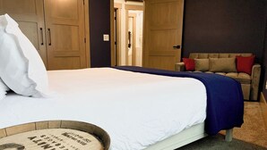 A bedroom with a bed, a wooden wardrobe, a sofa, and a small table with a barrel.