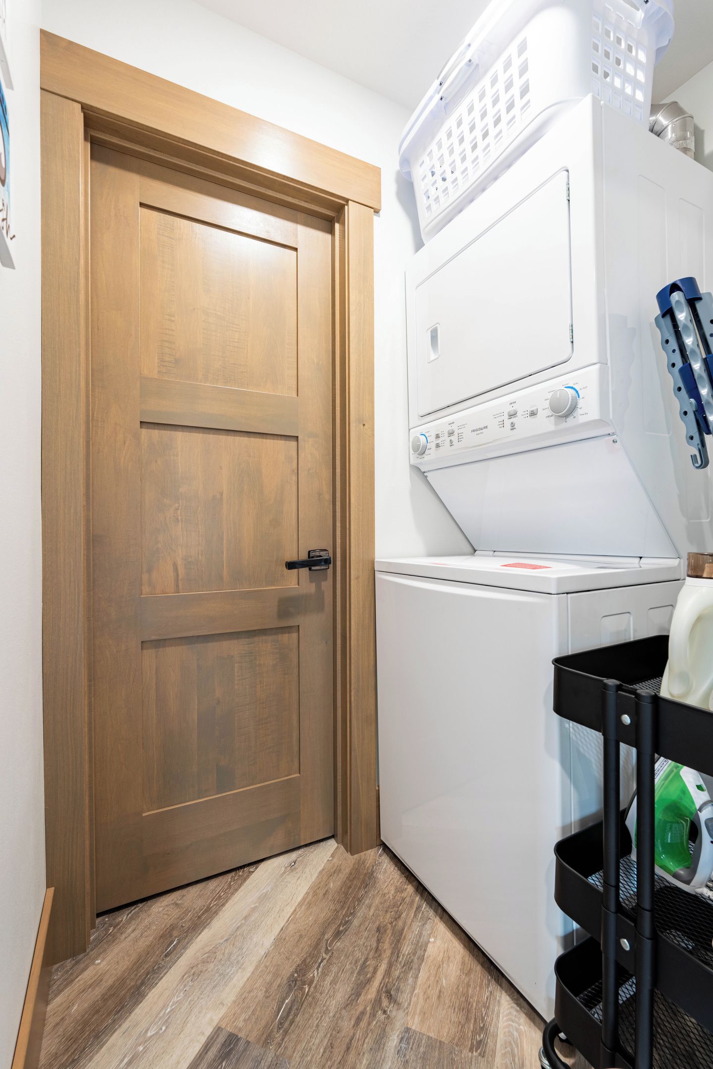 Un cuarto de lavandería con una puerta de madera, una lavadora y un tendedero.