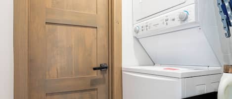 Un cuarto de lavandería con una puerta de madera, una lavadora y un tendedero.