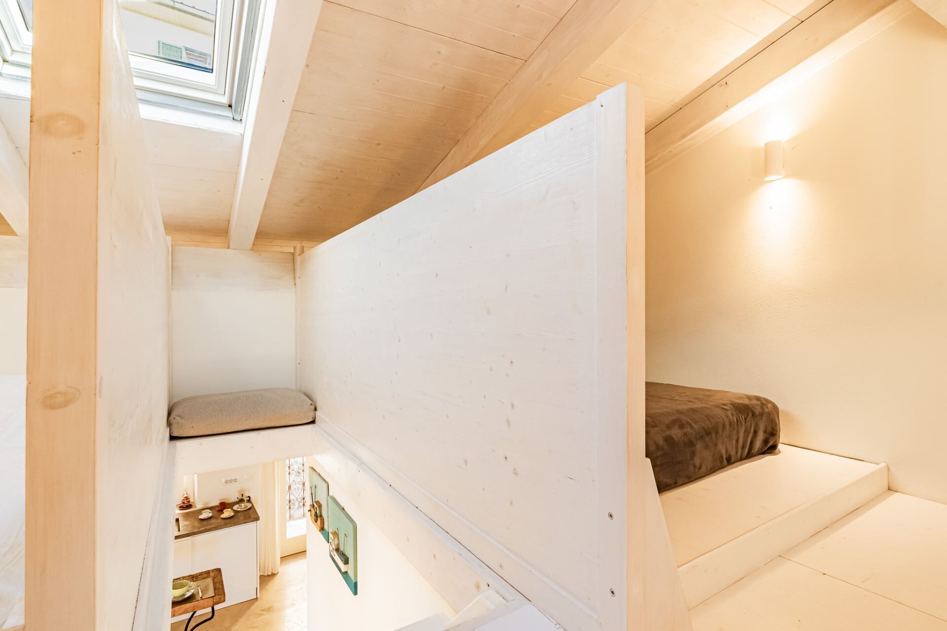 A compact room with a bunk bed, a small kitchenette, and a skylight.