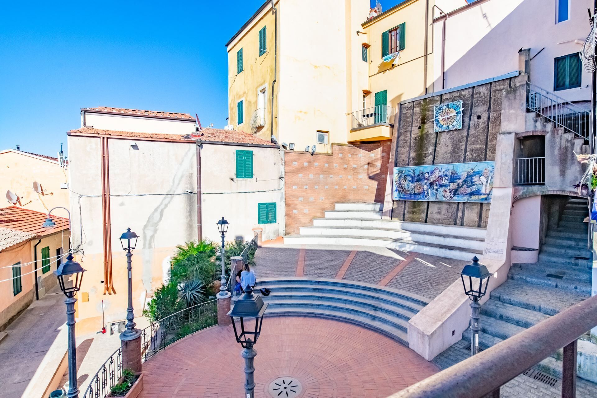 A circular plaza with a staircase leading up to a building with a mural.