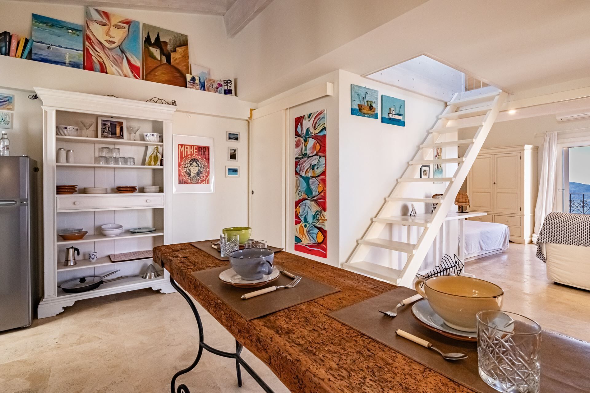 Una cucina moderna con un piano di lavoro marrone, mobili bianchi e una scala che conduce a una camera da letto.