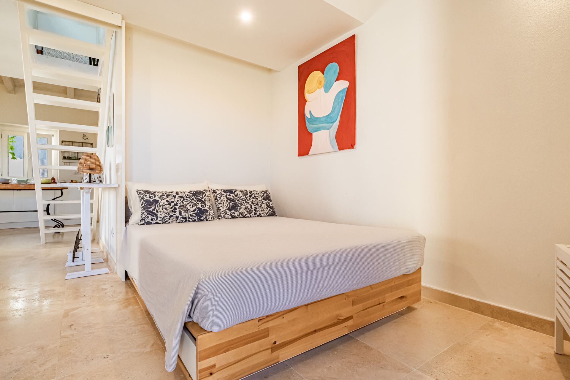 A bedroom with a wooden bed, a white wall, and a red abstract painting.