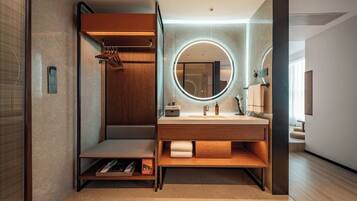 Un baño moderno con tocador de madera, un espejo redondo y una zona de ducha integrada.