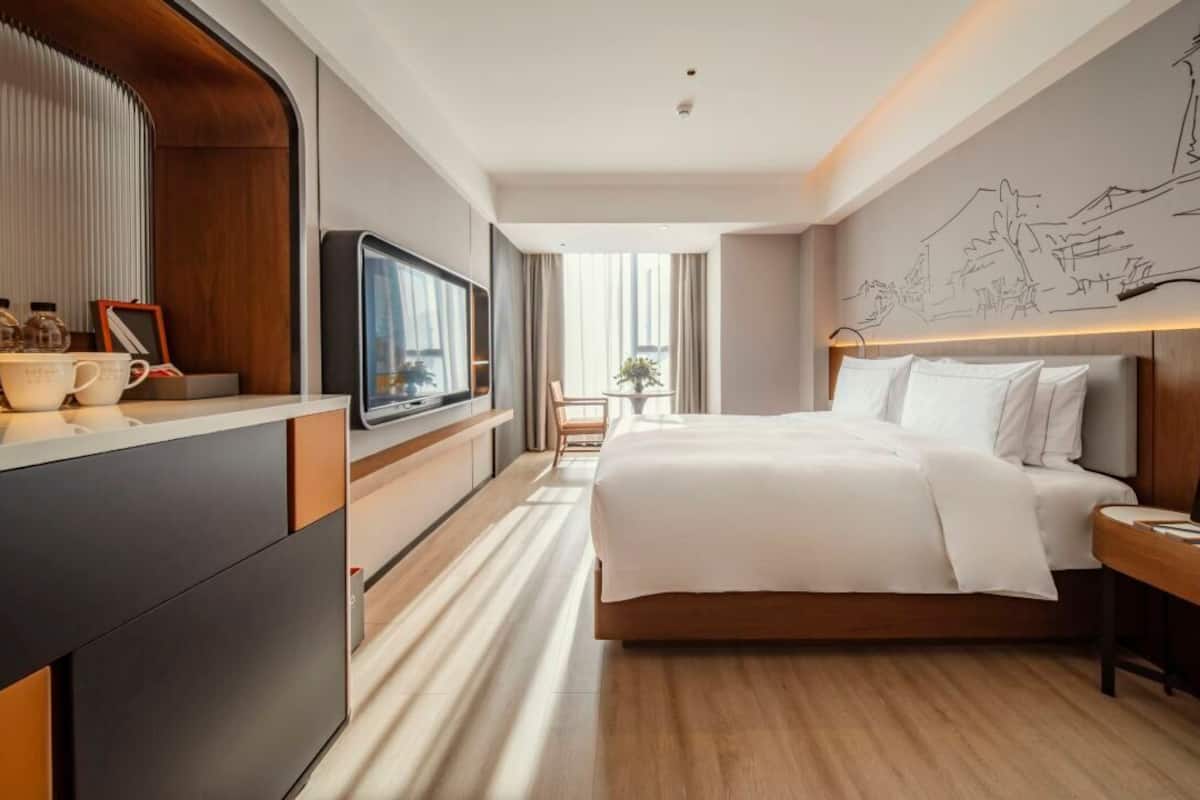 Hotelkamer met een groot bed, een televisie, een bureau en uitzicht op de stad.