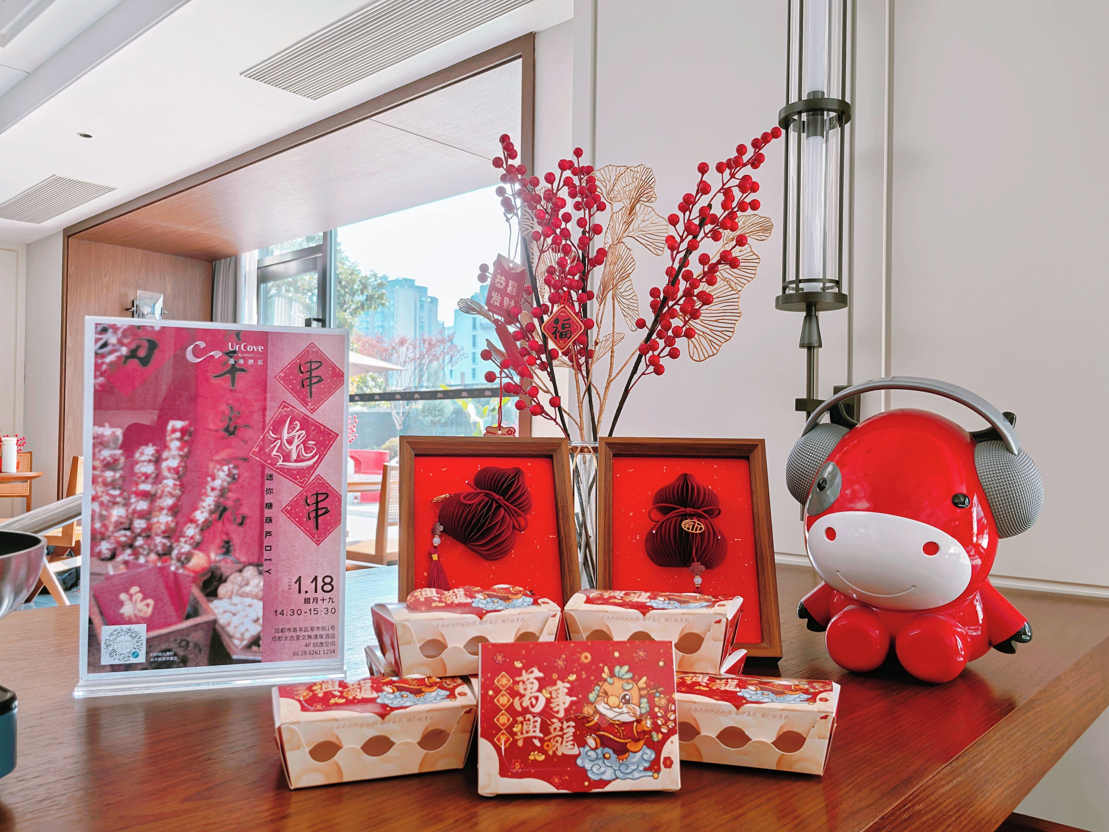 A room with a wooden table displaying red and white gift boxes, a red decorative item, and a framed sign with Chinese characters.