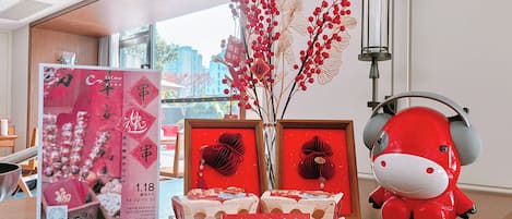 A room with a wooden table displaying red and white gift boxes, a red decorative item, and a framed sign with Chinese characters.