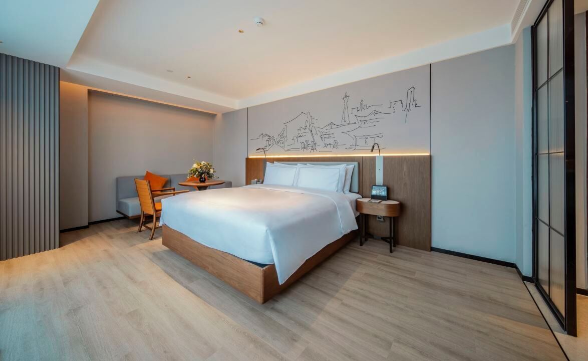 A modern hotel room with a large bed, a desk, and a chair.