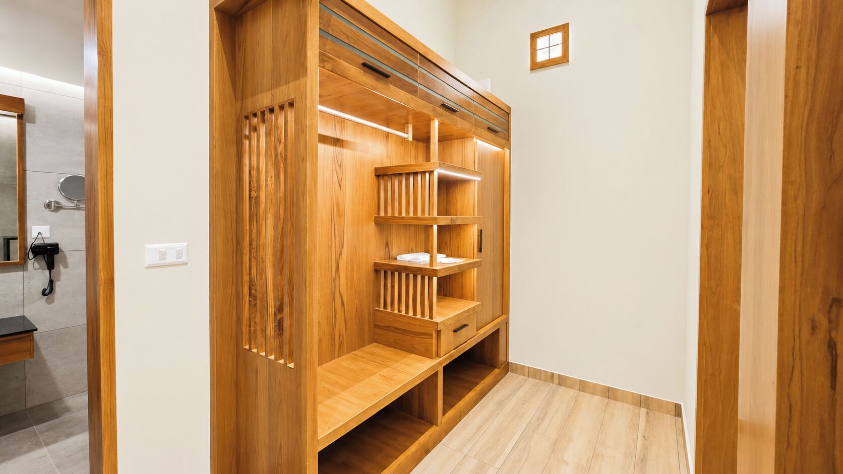 Une armoire en bois avec de nombreuses étagères et tiroirs, un miroir et un téléphone.