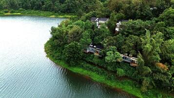 Traditional-style buildings nestle among lush greenery, surrounded by a serene lake.