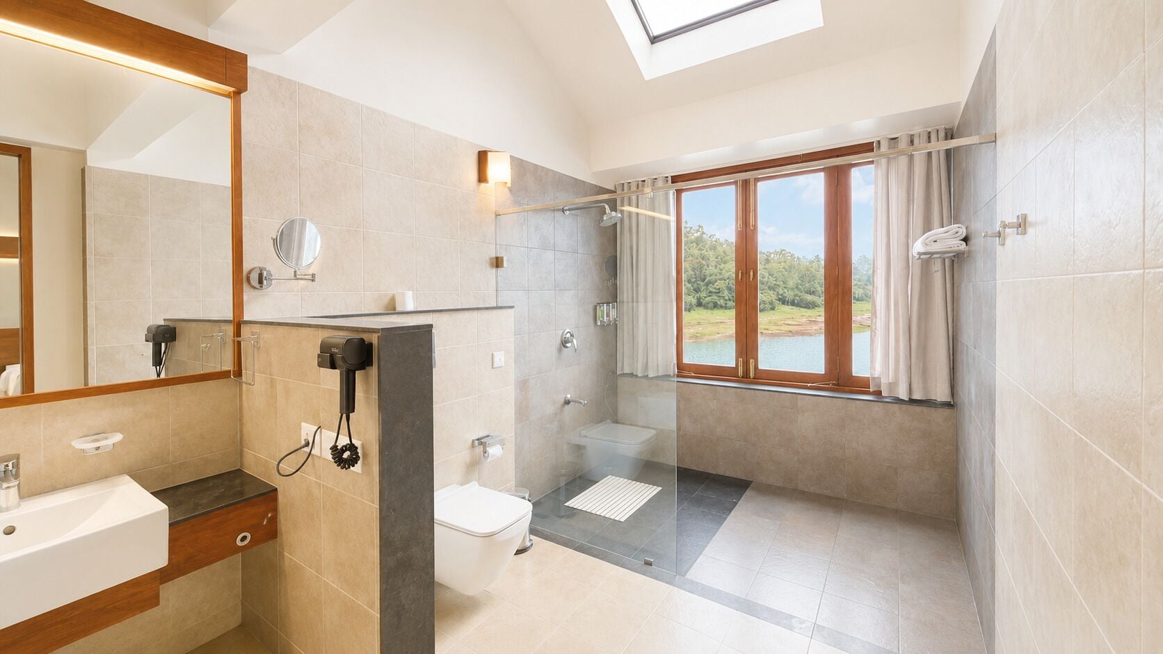 A modern bathroom with a skylight, a shower, a toilet, and a large window offering a view of the outdoors.