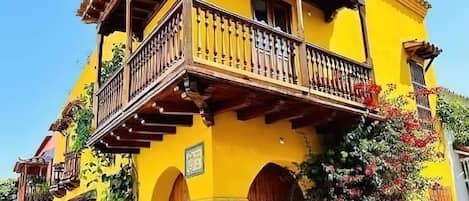 A yellow building with a wooden balcony and arched doors.