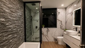 Un bagno moderno con una vasca, una doccia, un water e un mobile lavabo.